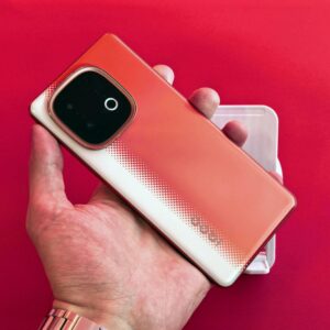 A vibrant smartphone held against a matching red background, highlighting its sleek design.